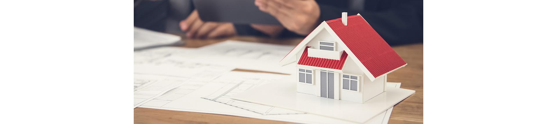 Modell eine Hauses auf Holztisch mit Papierstapel