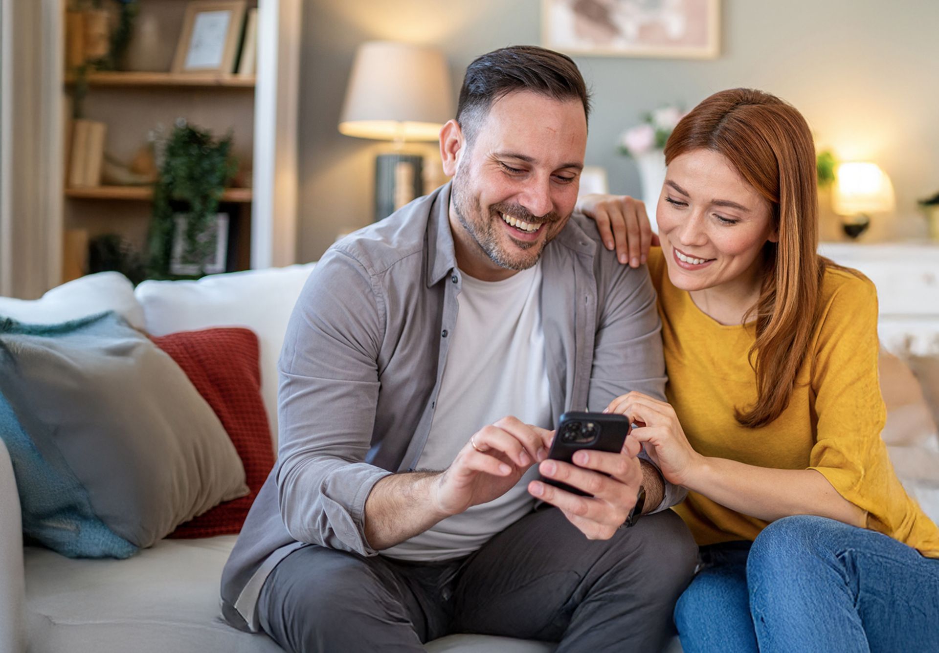 Paar sitzt auf dem Sofa und schaut auf Handy