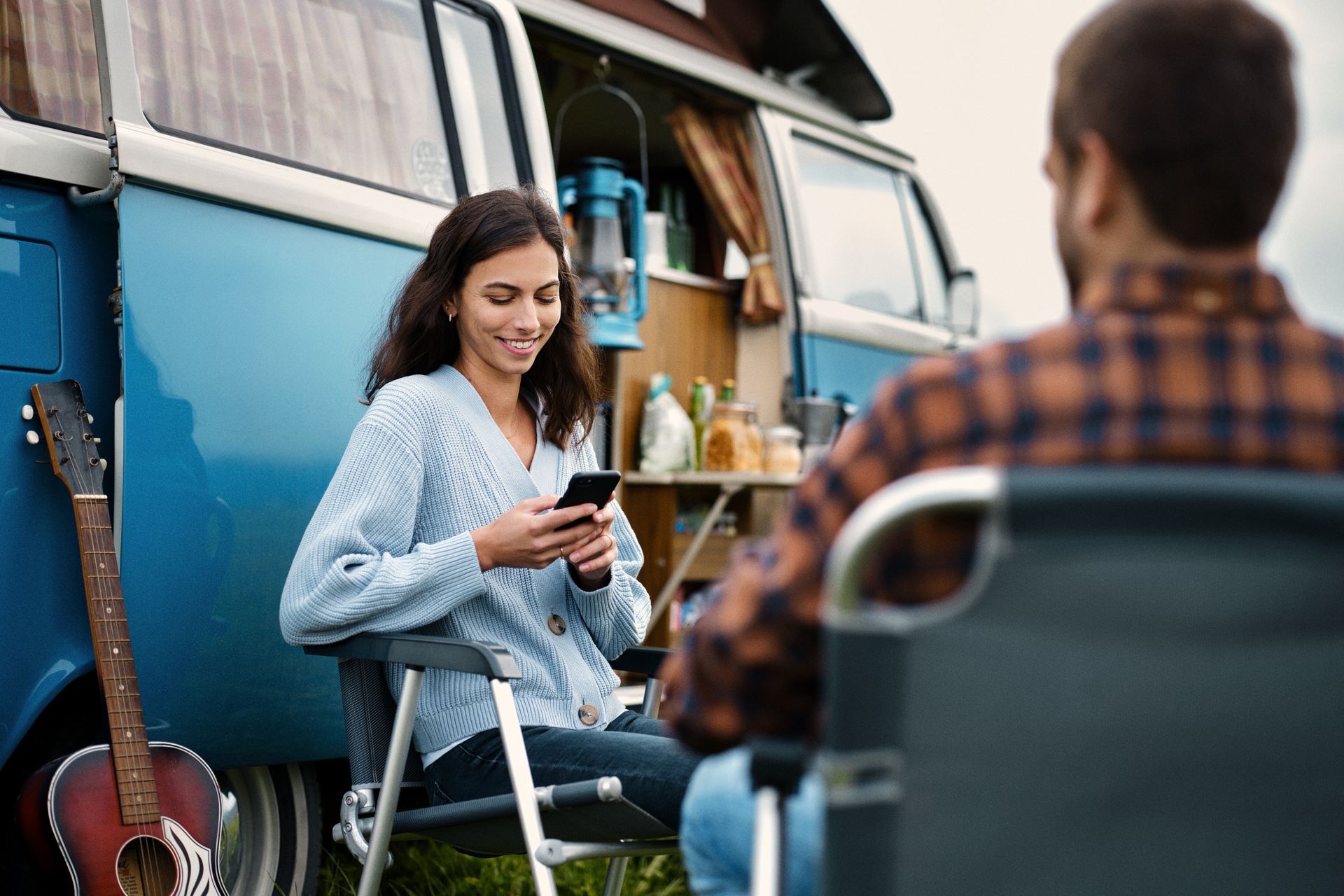 Frau am Smartphone vor Campingwagen