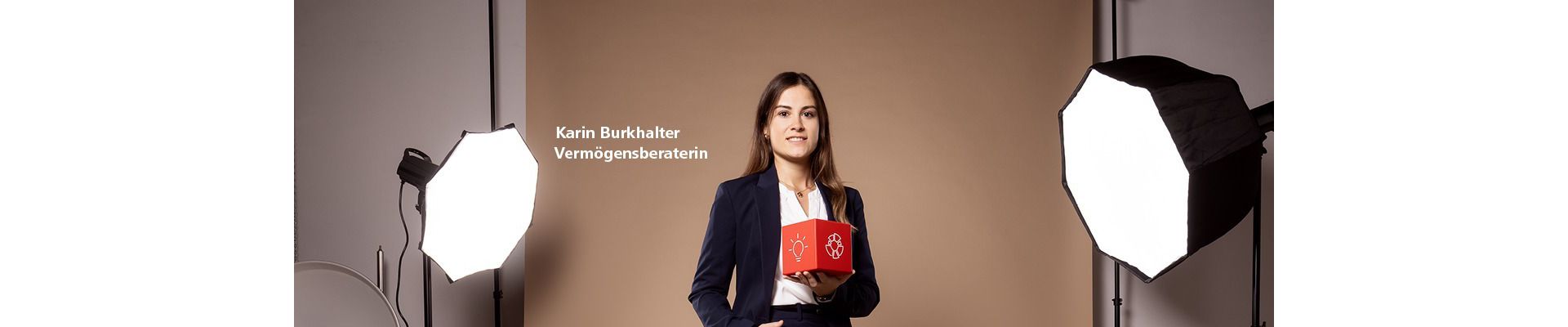 eine Raiffeisen-Mitarbeiterin im Studio mit einem roten Würfel