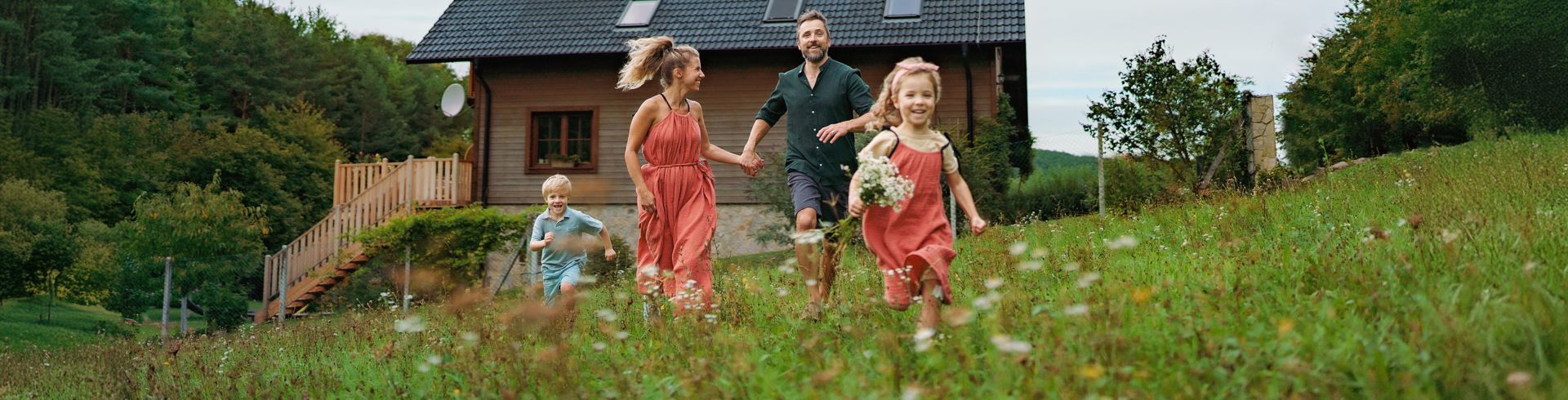 Familie springt in Gras vor Haus