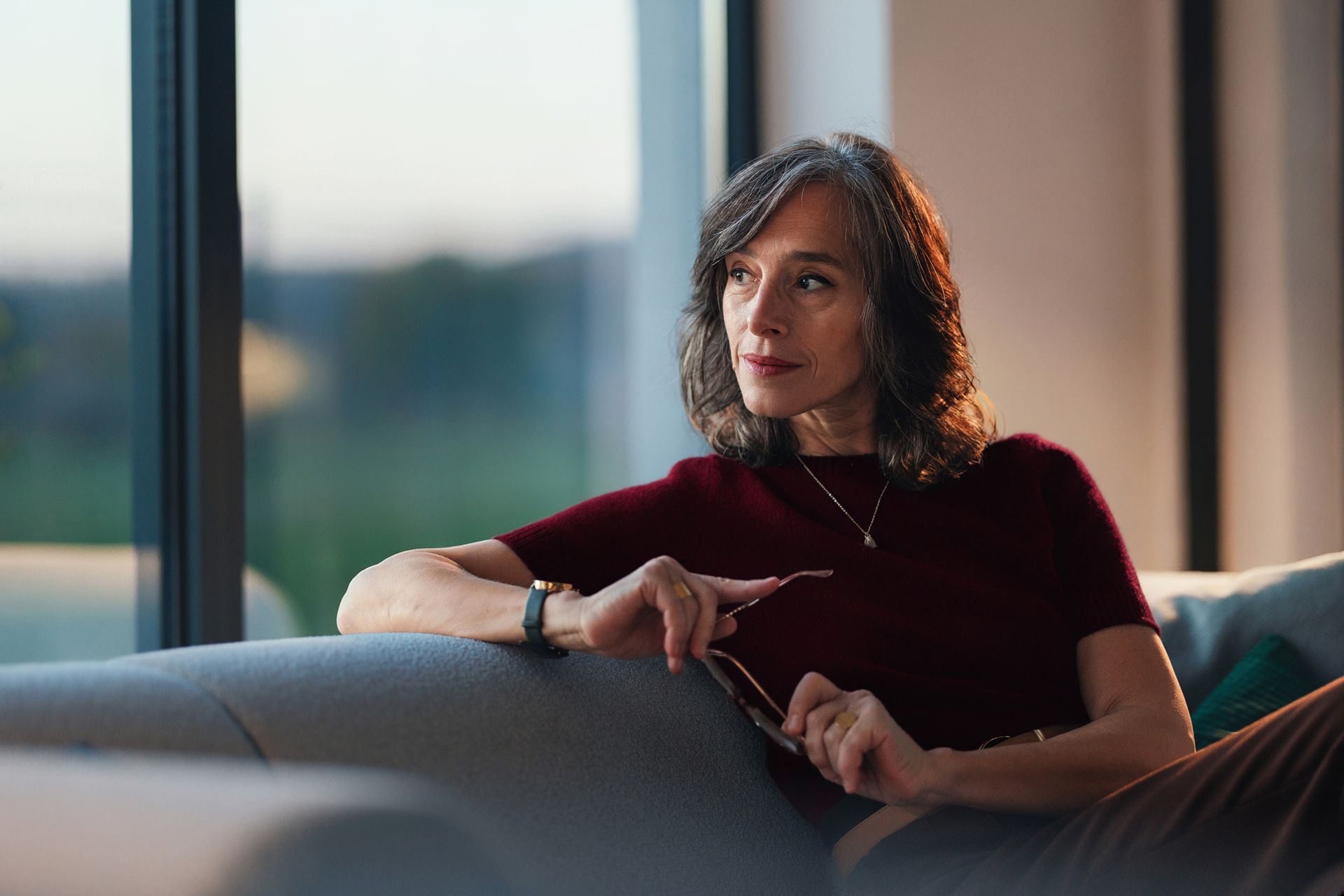 Frau sitzt auf dem Sofa und schaut aus dem Fenster