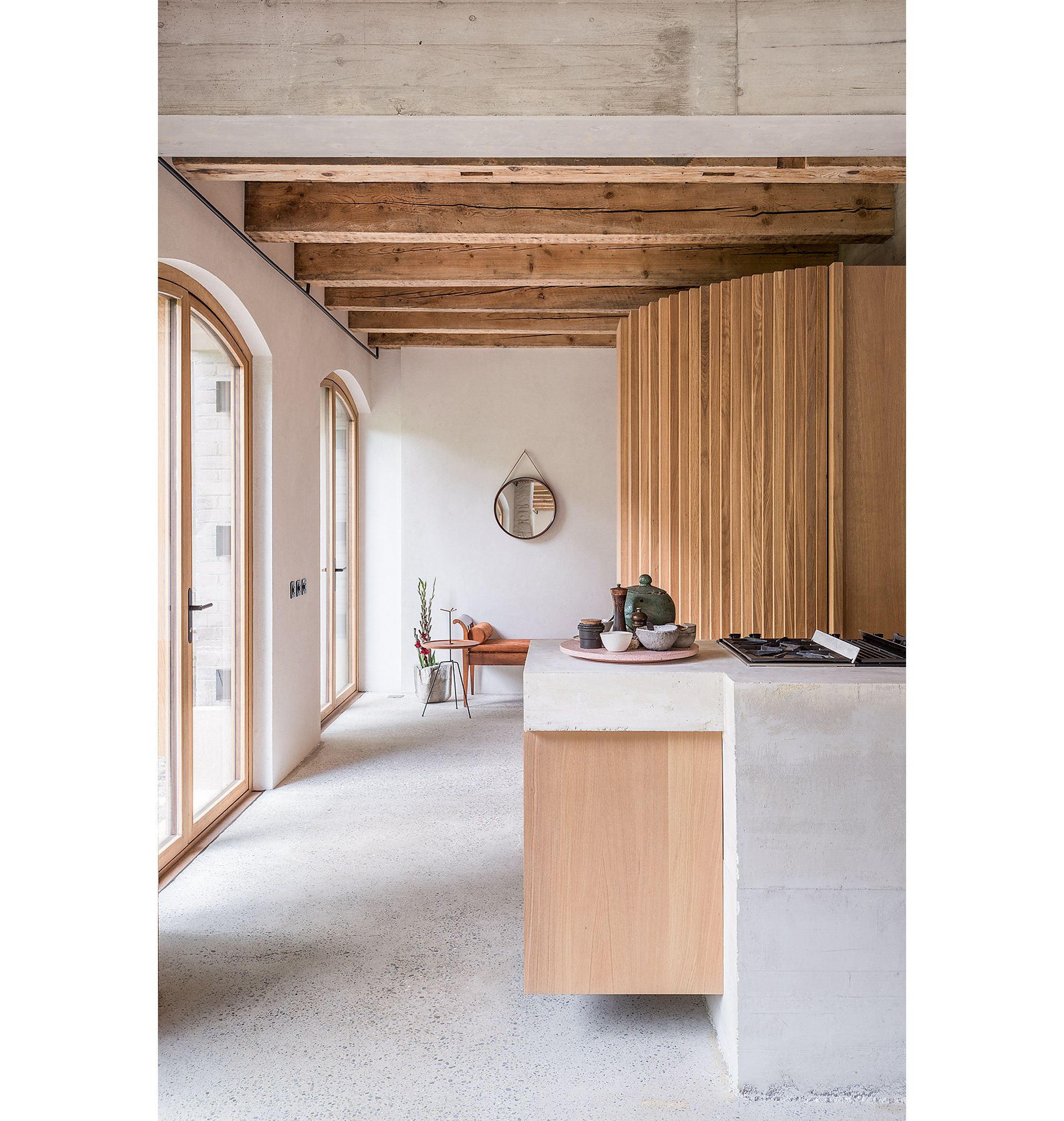 Des portes-fenêtres côté jardin rappellent les anciennes portes d’écurie. Le meuble habillé de bois derrière le coin cuisine abrite le vestiaire et la salle de bains des invités.