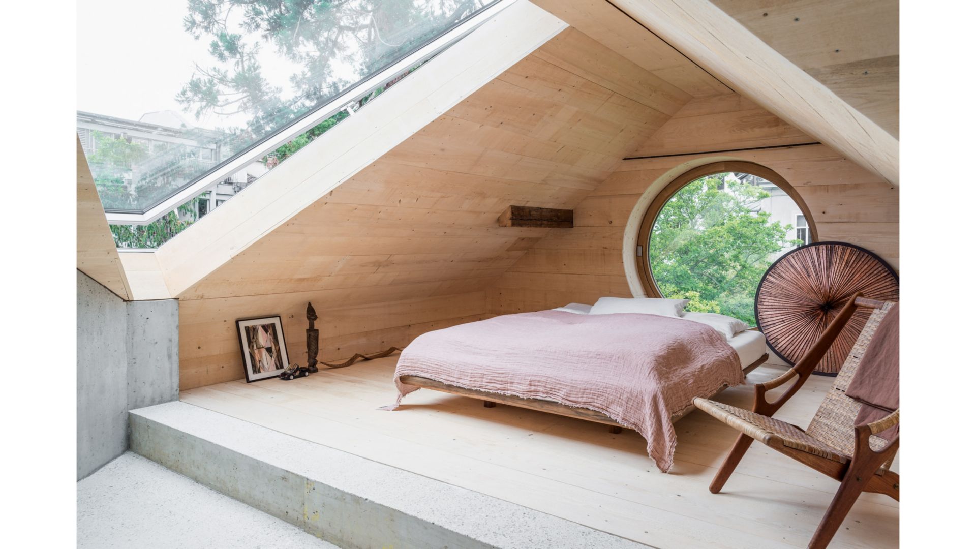 Une immense lucarne en forme de triangle ouvre la vue directement sur les nuages depuis la plateforme de couchage. (Petite sculpture en bois de Michel Pfister, illustration «Sans titre 2009» de Bernd Ribbeck)