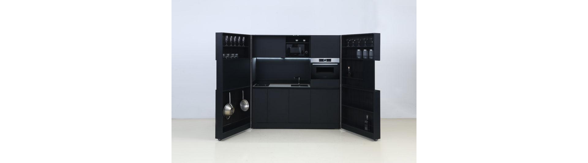 Deiskonzept conferisce alla mini cucina un'ulteriore sfaccettatura: quando è chiusa, «Pia» sembra un armadio da salotto con televisore integrato. Quando è aperta, è una cucina completamente attrezzata con lavastoviglie, frigorifero, cappa aspirante e spazio per riporre gli oggetti più vari. Questo miracolo salvaspazio può essere usato in posizione indipendente, montato a una parete o inserito in una nicchia. Foto: Deiskonzept