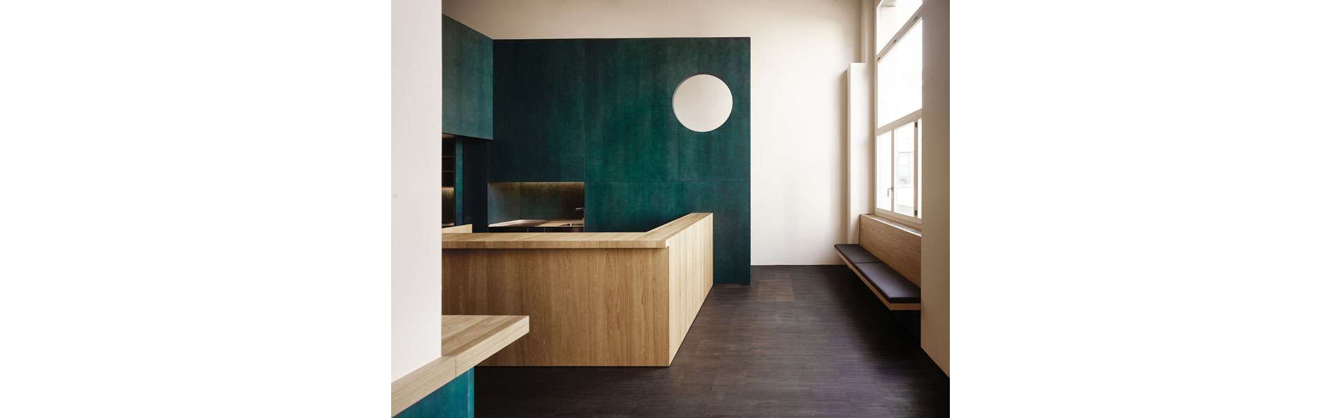 Ein hochwertiger Holzbau aus grün lasiertem Sperrholz begleitet den Nutzer durch den Raum.