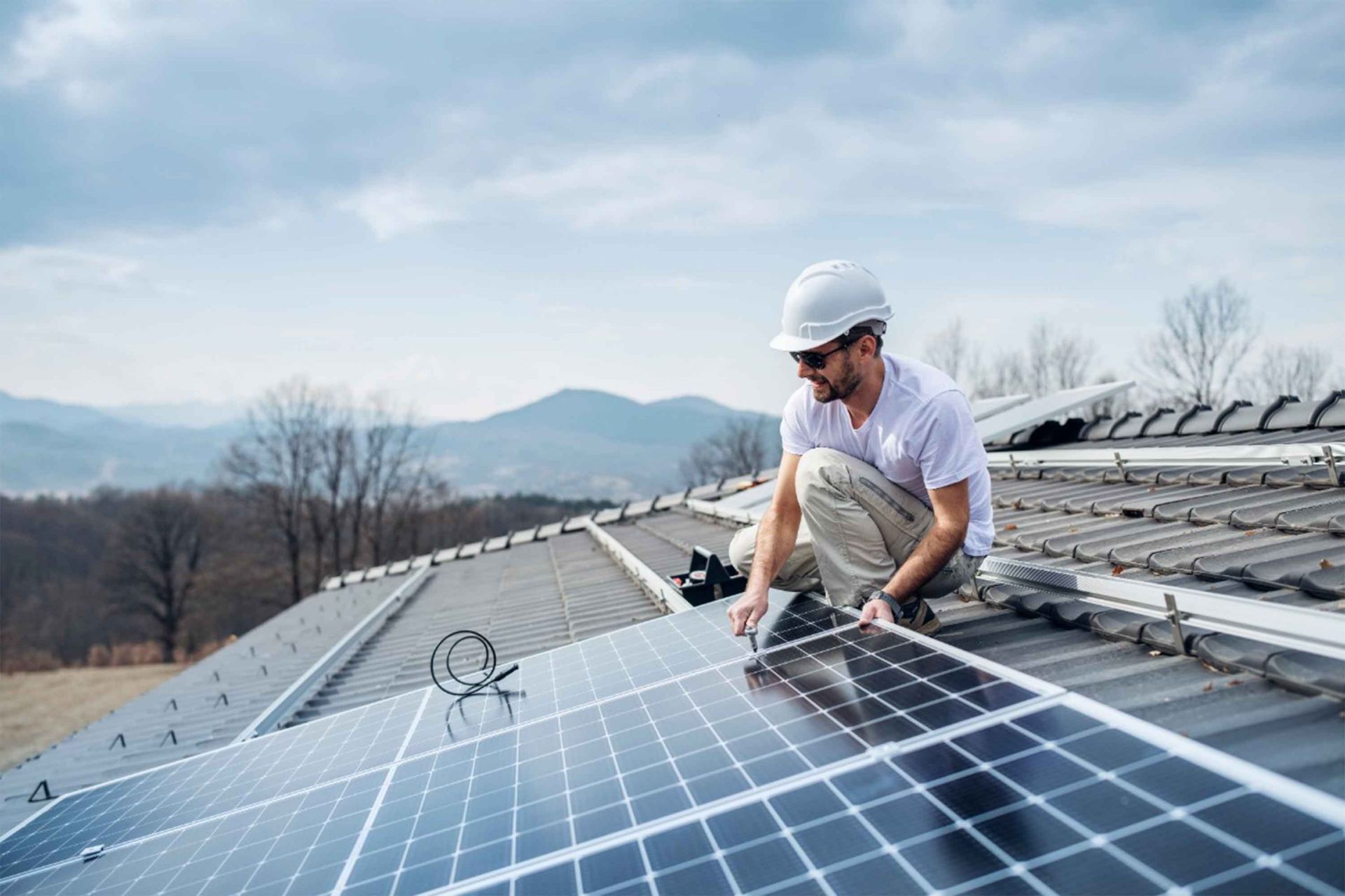 Mann auf Dach mit Solaranlage