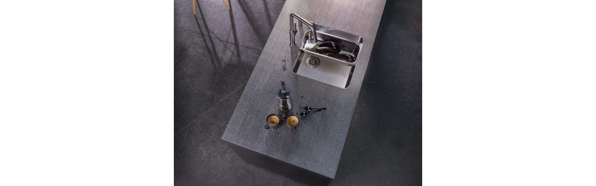 La finitura superficiale è particolarmente importante nelle aree umide della cucina. Se volete combinare tutti i vantaggi di una superficie in acciaio, resistente allo sporco, robusta, da pulire, con un look virtuoso, non potete lasciarvi sfuggire «BlackRange Industrial». Una lastra di acciaio grezzo nero che viene accuratamente levigata a mano, trasformandosi in una superficie dalla struttura esclusiva con accenti argentati. Foto: Suter Inox