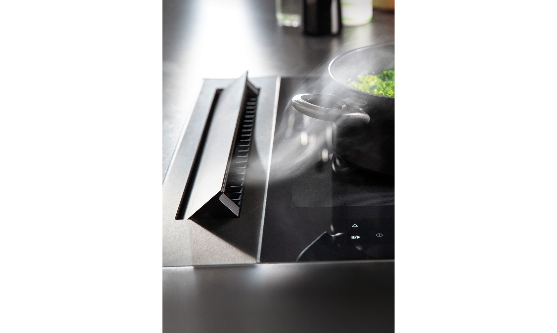 Dicke Luft ist auch in der Küche nicht gefragt: Dezent am Kochfeld angeordnet, saugt «Basso Flex» die Kochdünste effizient direkt nach unten ab. Fast unbeschränkt in Grösse und Ausführung, ermöglicht der Dunstabzug die Wahl eines Kochfelds, das in seiner vollen Fläche frei nutzbar ist. «Basso Flex» ist in Schwarz und Edelstahl, als Abluft- oder als Umluftsystem erhältlich und um Platz im Unterschrank zu sparen, werden die Lüfter im Sockel platziert. Foto: Wesco