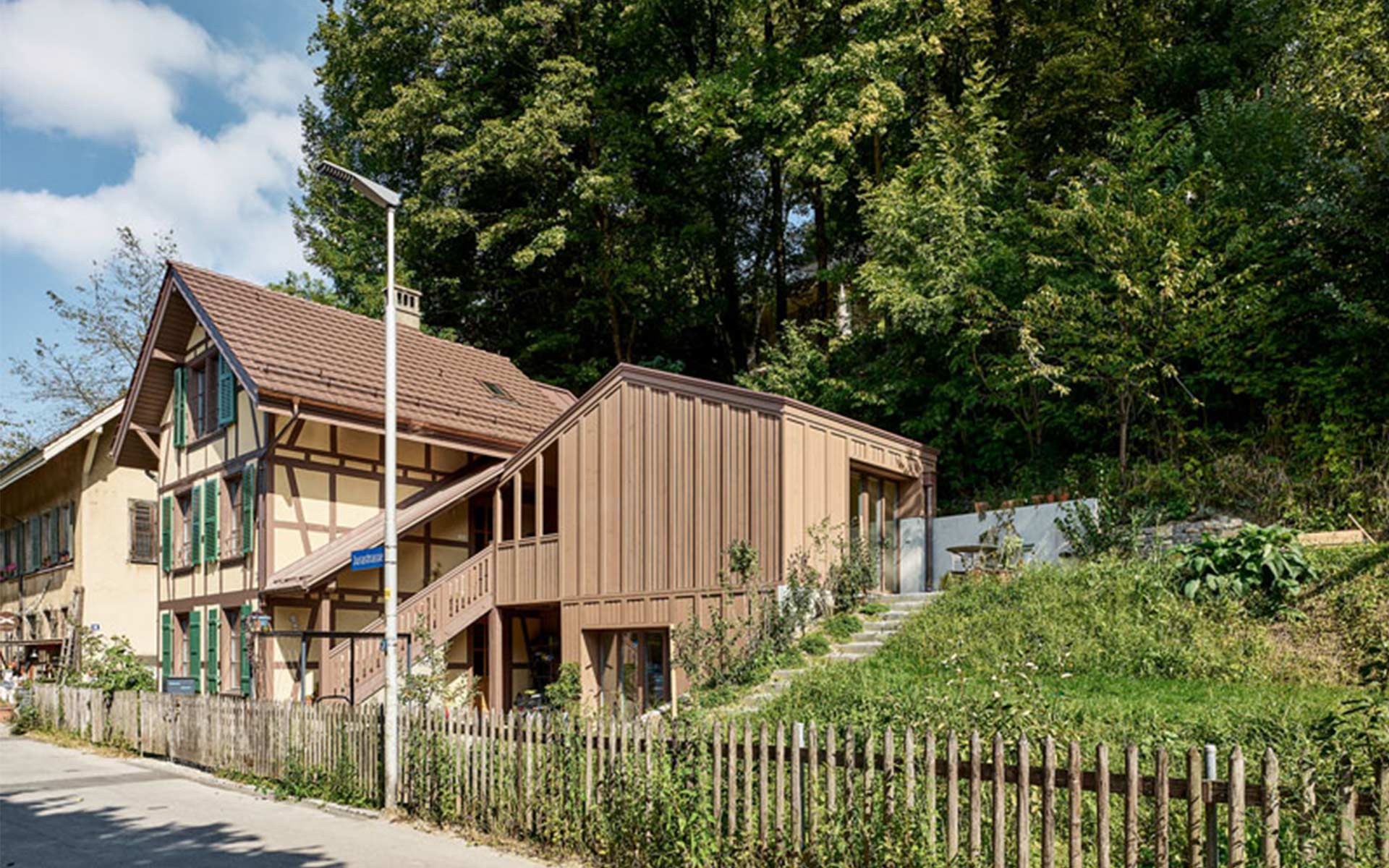 L’extension en forme de hotte est reliée à l’ancien escalier extérieur. De l’extérieur, on ne peut que deviner qu’elle agrandit également l’ancienne bâtisse à l’arrière.