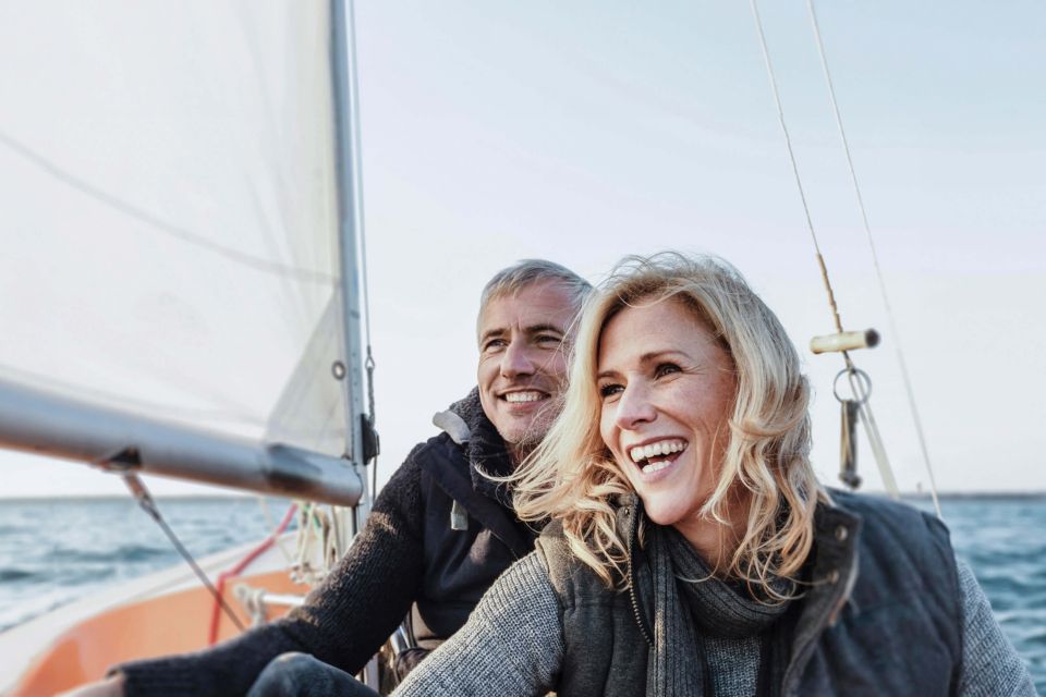 Ein glückliches Rentnerpaar segelt entspannt auf einem See.