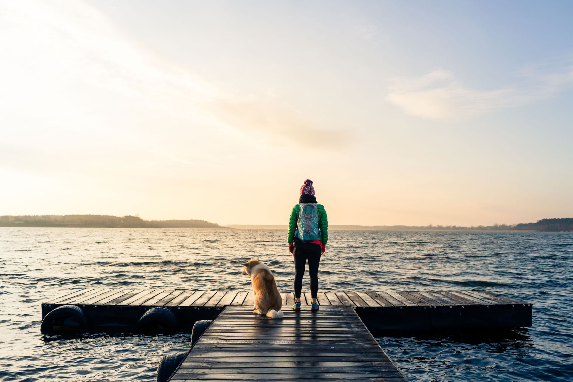 Frau mit Hund auf Steg am See