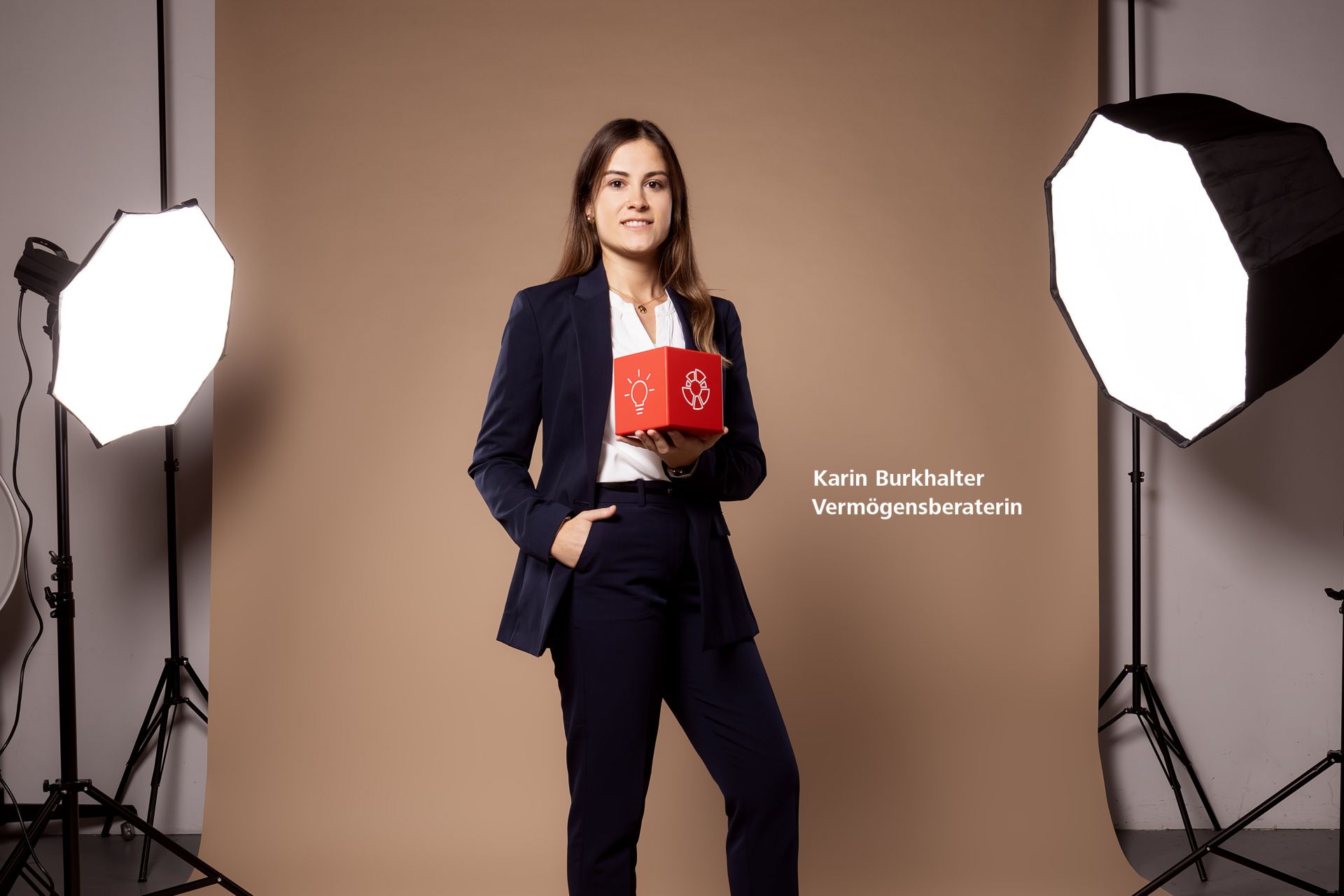 eine Raiffeisen-Mitarbeiterin im Studio mit einem roten Würfel