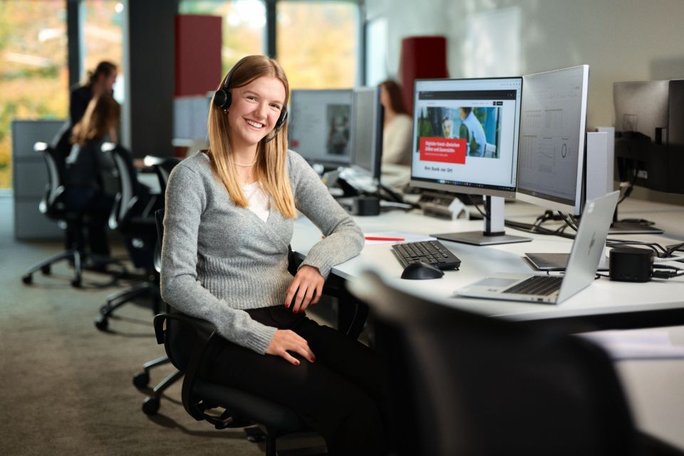 Junge Frau sitzt im Büro und lächelt in die Kamera