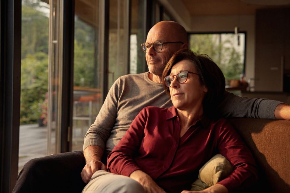 Una coppia è seduta sul divano e guarda fuori dalla finestra