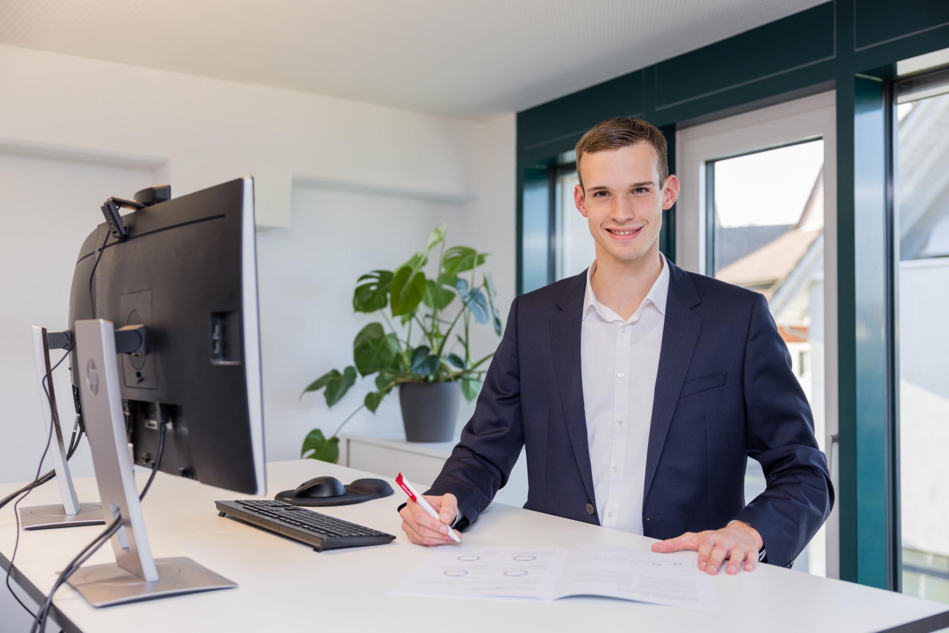 Mitarbeiter der Raiffeisenbank Regio Frick-Mettauertal am Arbeitsplatz lächelt in Kamera.