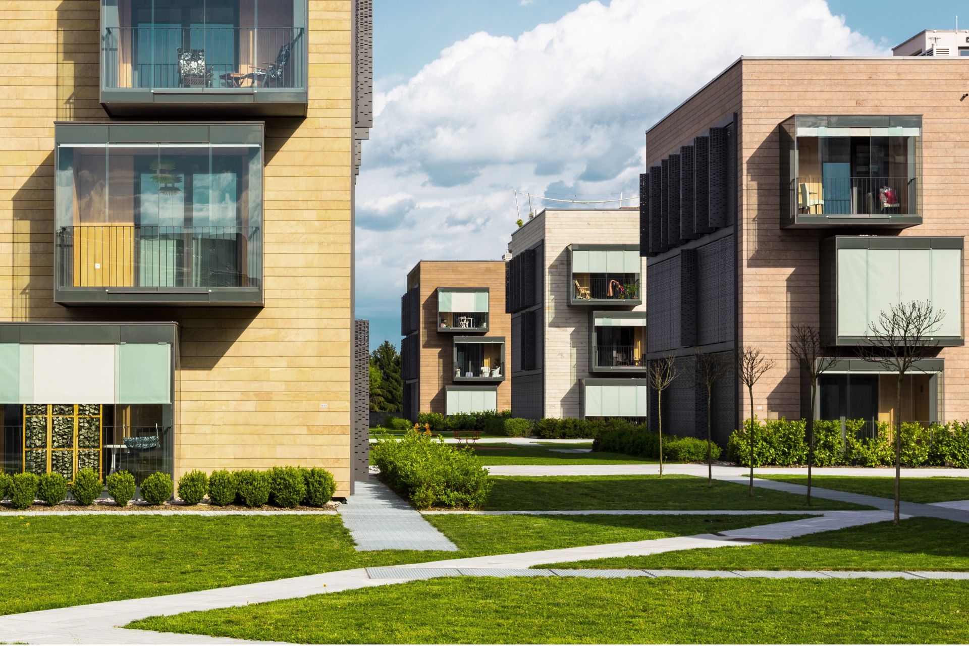 Moderno complesso residenziale con balconi e spazi verdi all'aperto sotto un cielo azzurro.